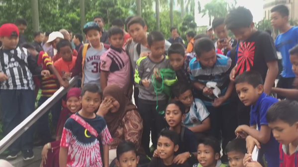 Fans of Malaysia's returning Paralympic athletes patiently wait for their arrival below Petronas twin towers , chanting  Malaysia Boleh   