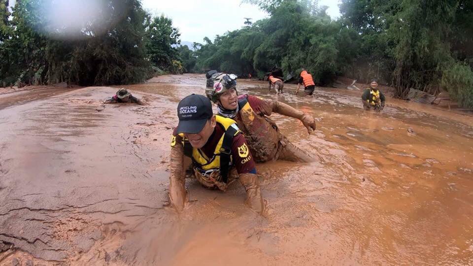 A photo published by ABC Laos News showing rescuers wading through deep mud in search for the remaining 123 people missing in Laos after a dam collapse