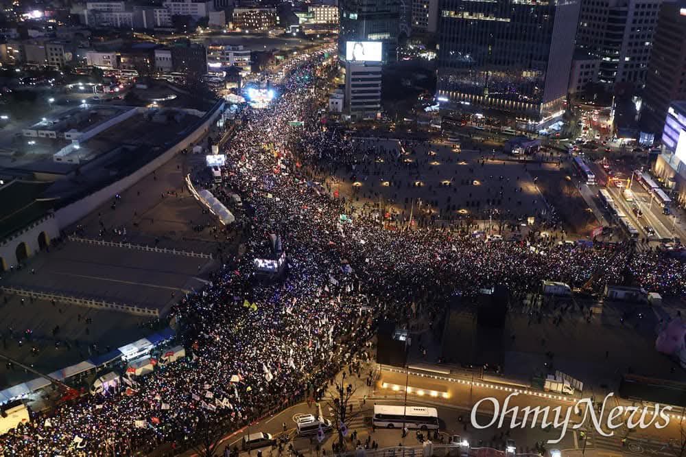 Honderdduizenden Zuid-Koreanen marcheren door het centrum van Seoul en eisen het onmiddellijke aftreden van Yoon Suk Yeol, niet afgeschrikt door temperaturen onder het vriespunt. Op de laatste zaterdag van 2024 schittert een oceaan van aanmoedigingsstokken als sterren, die de bitterkoude nacht van Seoul verlichten terwijl meer dan 500.000 Zuid-Koreanen protesteren om te eisen dat Yoon Suk Yeol aftreedt vanwege zijn kortstondige staat van beleg.